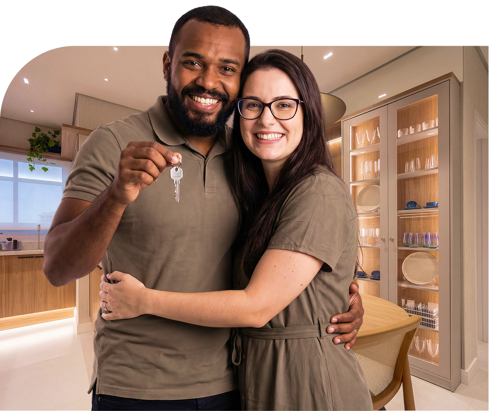 Casal feliz segurando as chaves do novo apartamento, com o interior decorado do Bella Vida Graminha ao fundo